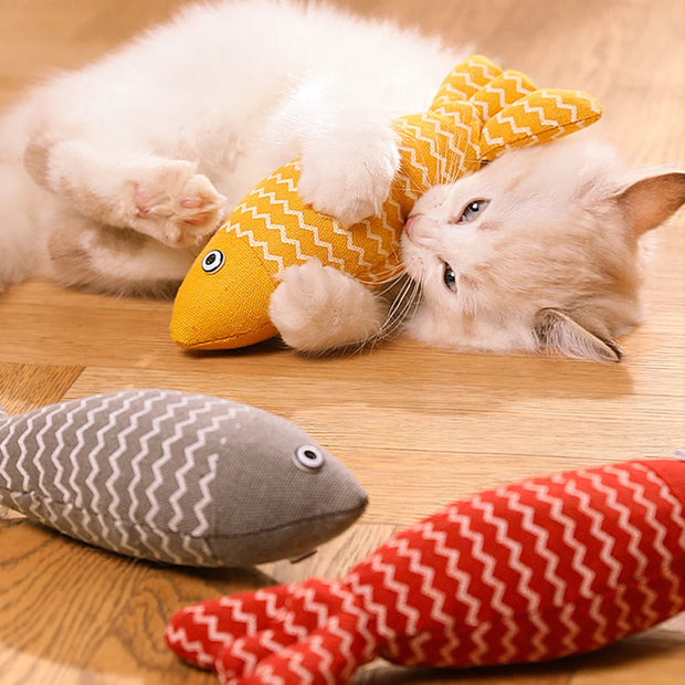Cat playing with a yellow Catnip Fish Plush Toy  on a wooden floor.