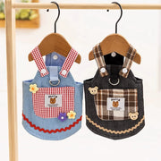 Two Cute Pet Overalls Dress Denim and Plaid Style with checkered designs hanging on wooden hangers against a white background.