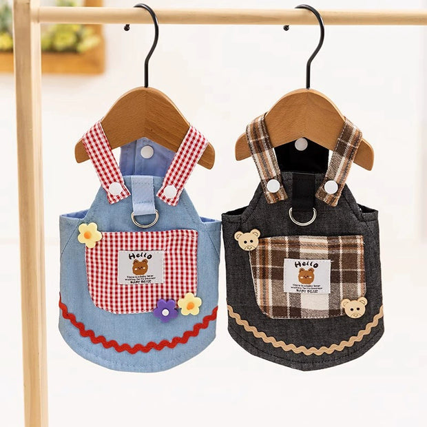 Two Cute Pet Overalls Dress Denim and Plaid Style with checkered designs hanging on wooden hangers against a white background.