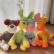 Four colorful knitted Plush Animal Rope Dog Toys on a wooden surface with a light curtain background.