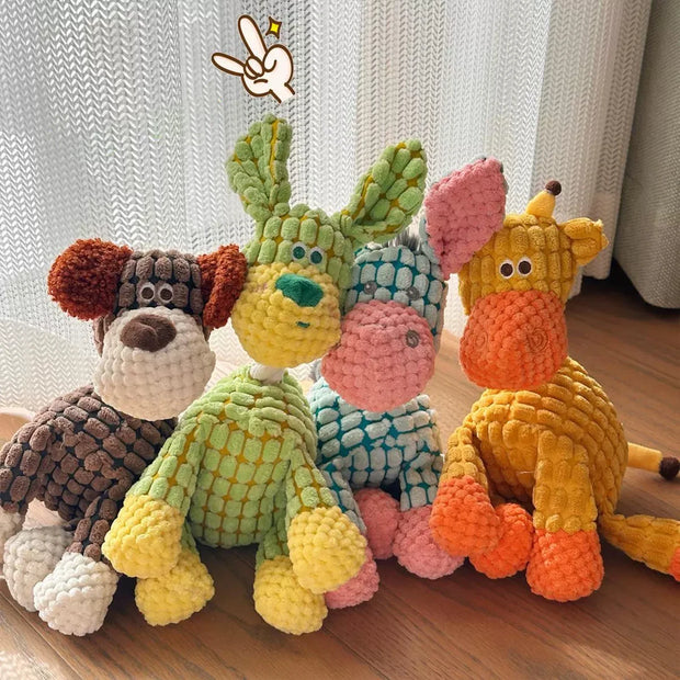 Four colorful knitted Plush Animal Rope Dog Toys on a wooden surface with a light curtain background.