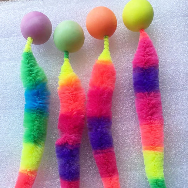 Colorful Rainbow Tail Cat Toy Balls with fuzzy strings on a textured white background