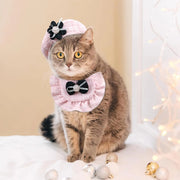 Cat wearing a pink Elegant Cat Costume Set, sitting on a white surface with Christmas decorations.
