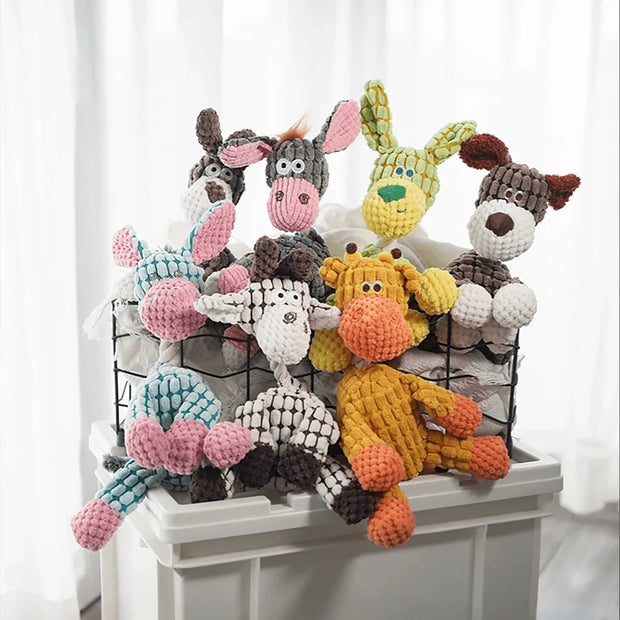Collection of colorful knitted Plush Animal Rope Dog Toys on a white surface with a white curtain background.