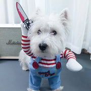 Small white dog wearing a Killer Doll Pet Costume with a red and white striped arm and blue overalls with 'Good Dog' text.