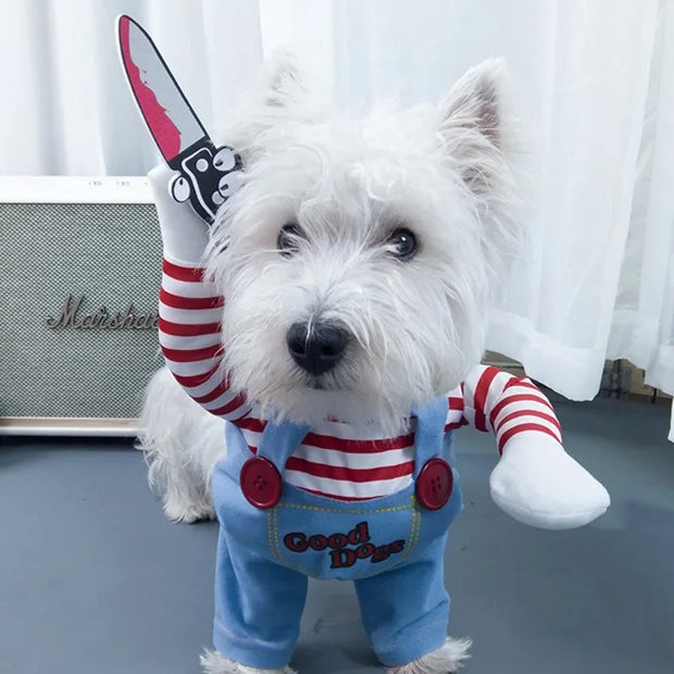 Small white dog wearing a Killer Doll Pet Costume with a red and white striped arm and blue overalls with 'Good Dog' text.