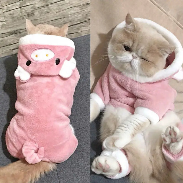 Cat in a pink Dinosaur Hoodie Costume with white accents on a wooden floor.