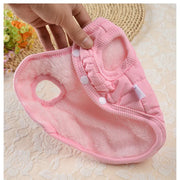 Pink Winter Dog Jacket with white buttons held by a hand on a textured beige surface.