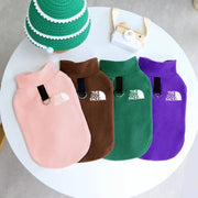 Four dog Fleece Dog Jacket in pink, brown, green, and purple on a white surface with 'The Dog Face' logo.