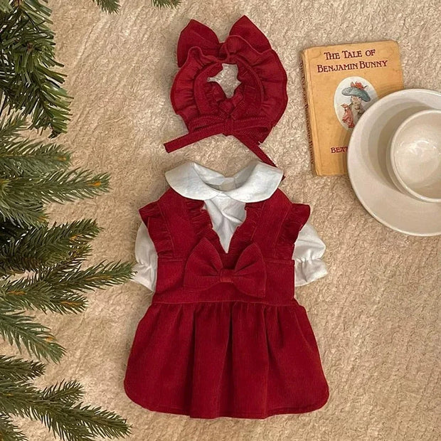 Red Puppy Bow Dress Set with white collar and matching headband on a textured surface with Christmas decorations.