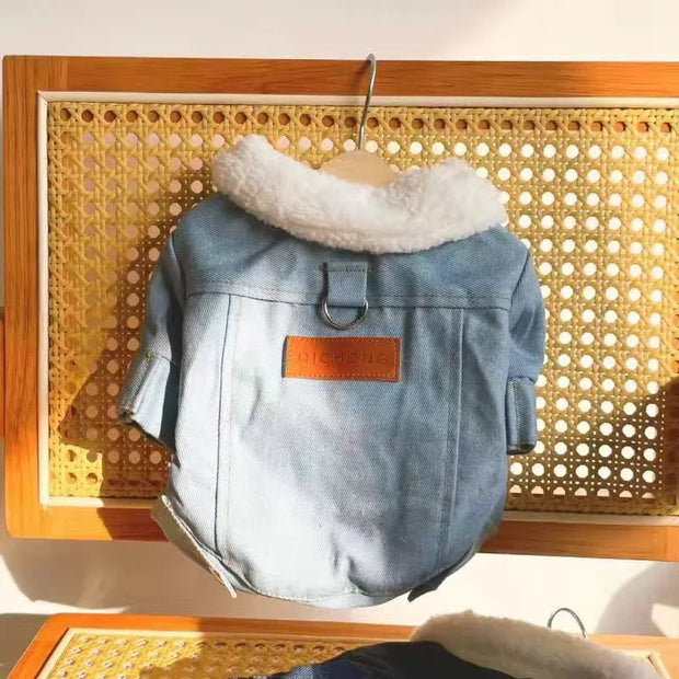 Blue Denim Dog Jacket with white fur lining on a wooden hanger against a woven background.