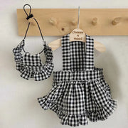 Black and Checkered Pet Dress with Matching Bib on a wooden hanger against a white wall.