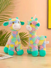 Two colorful Plush Giraffe Dog Toy resembling a cow and a giraffe on a wooden surface with a leafy green background.