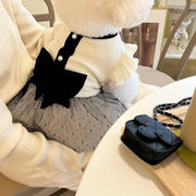 Pet wearing a white Elegant Black Bow Dress, sitting on a chair with a black handbag beside them.