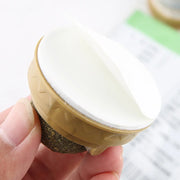 Round object with textured base held by a Catnip Ball Toy and hand against a blurred background