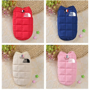 Four Winter Dog Jacket in red, blue, beige, and pink with 'The Dog Face' logo on a textured surface.