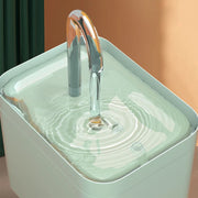 Modern Pet Water Fountain Metallic faucet pouring water into a square container with a blurred background