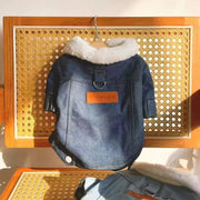 Denim Dog Jacket with white fur lining and orange patch on a wooden surface