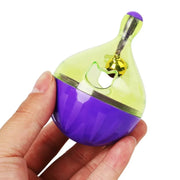 Hand holding a purple and green Shaking Q Pet Treat Dispenser Toy with a white background