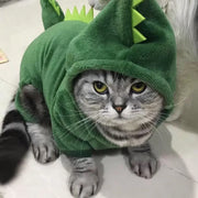 Cat wearing a green Dinosaur Hoodie Costume on a light-colored floor.
