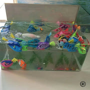 Clear fishbowl with colorful Interactive Electric Swimming Fish Toys inside on a white surface.