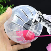 Clear Plastic Hamster Gerbil Rat Exercise Toy with pink interior held by a hand, being filled with water from a faucet with hand against a dark background.