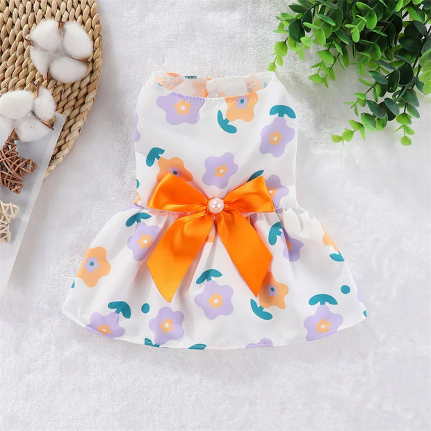 Summer Princess Dress with an orange bow on a textured surface with cotton and greenery.
