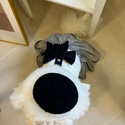 Small dog wearing a black and white Elegant Black Bow Dress on a tiled floor.