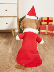 Dog wearing a Santa Claus Pet Costume outfit standing on a wooden floor with Christmas decorations.