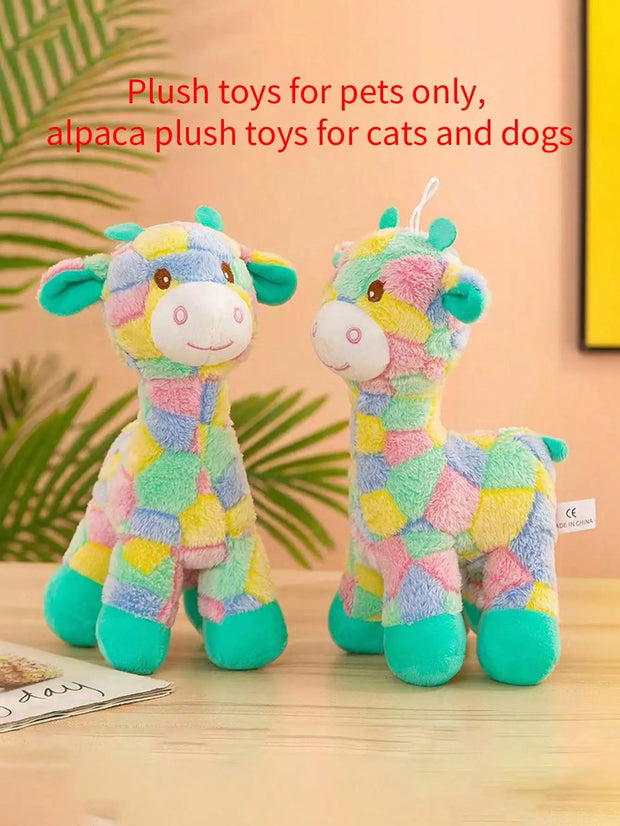 Two colorful alpaca Plush Giraffe Dog Toy on a wooden surface with a blurred green leafy background.