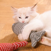 White cat playing with a red and gray Catnip Fish Plush Toy  on a wooden floor