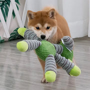 Dog playing with a green and gray Plush Animal Dog Toys on a wooden floor.