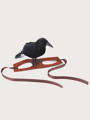 Black crow perched on a 1pc-Halloween Crow themed Pet Headwear with a brown strap on a light beige background