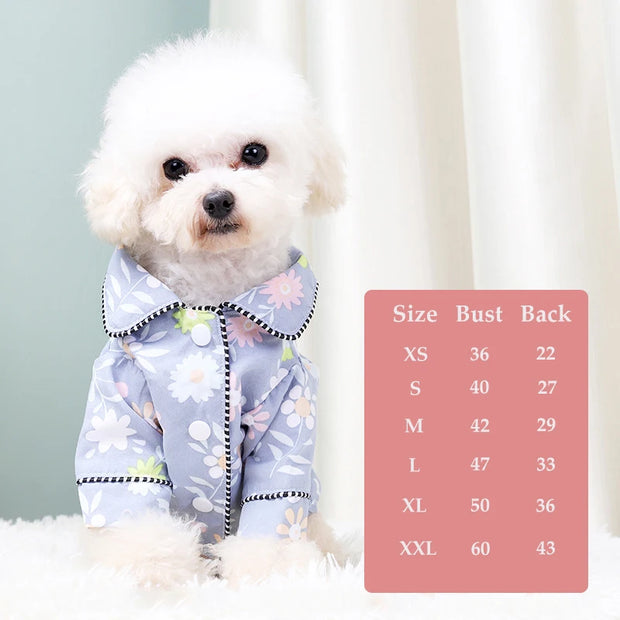 Small white dog wearing a floral hooded Elegant Pet Shirt with a size chart on a light background