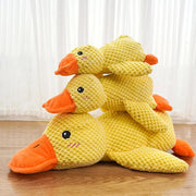 Three yellow and orange Dog Calming Duck Plush Toy on a soft surface