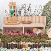Small animal enclosure with a Wooden Hamster Hideout House with Dual Compartments feeder, and water bottle on a grassy background.